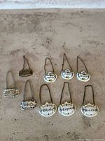 Overall view of 9 liquor labels displayed on a surface, including 6 fine china labels and 3 metal labels