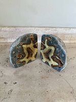 Front facing photo of the pair of bookends showing the polished crystal interiors with septarian patterns and natural stone exterior on a light background.