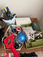 Various assorted hand tools and hardware items displayed in containers on a wooden surface