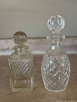 Front view of both decanters side by side showing body patterns and stoppers