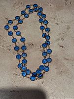 Full view of the blue crystal beaded long chain necklace with gold-tone metal links laid flat to show full length and design.