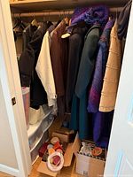 Closet view showing coats, jackets, cardboard boxes on floor and plastic drawers