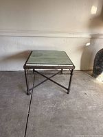 Full view of square coffee table showing stone marble top and metal frame base from above and front angle.