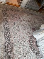 Angled view of full rug showing floral pattern and borders on hardwood floor