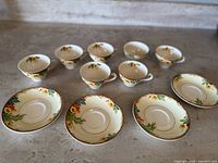 Photo showing six teacups and six saucers arranged in pairs with floral and gold trim design.