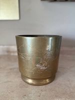 Front view of brass planter showing etched mountain and tree scene