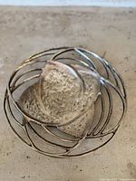 Close-up photo showing the bowl's textured central leaf-shaped section and outer open wire circular frame.