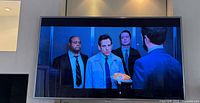 Front view of Samsung Smart TV mounted on wall displaying a scene from a movie.