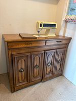 Singer Touch-Tronic 2010 sewing machine set into a wooden cabinet with storage drawers and paneled doors.