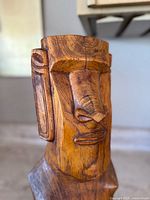 Close up photo of the Moai figure front showing carved face details, wood grain and cracks.