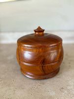 Side view of the vintage wooden storage box showing its rounded shape and wood grain.