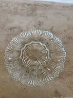 Top-down view of the clear glass vintage Anchor Hocking deviled egg plate, showing the scalloped edge, ribbed oval indentations for eggs, and starburst center pattern.