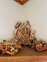 Angel tree topper sitting on a wooden shelf showing whole figure partially wrapped and folded fabric details.