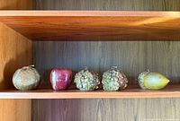 Five vintage Italian candles shaped like various fruits and nuts arranged on a wooden shelf.