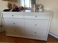 Front view of white wooden dresser with two small top drawers and three full-width lower drawers, metal knob handles