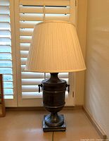 Full side view of vintage brass urn table lamp with cream pleated shade