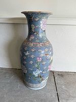 Front view of the tall Chinese porcelain vase showing detailed floral and butterfly patterns on a blue background.