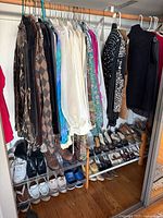 Full view of hanging garments on wooden rod with shoe rack below showing multiple pairs of shoes