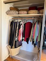 Photo showing hung women's clothing and pillows above on closet shelf