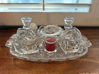 Top view of crystal set on wooden surface with four candle holders and an oval tray, showing clear glass and vintage cut design.