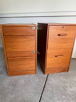 Front view of two vintage teak wood filing cabinets showing drawers and locks
