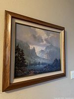 Framed mountain landscape artwork hanging on a beige wall, showing the composition and frame detail.