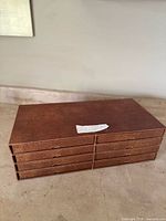 Brown leather-like multi-drawer organizer box containing plates, closed.