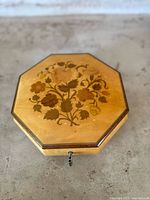 Top view of octagonal wooden music box with floral marquetry design on lid