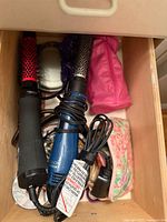 Drawer containing vintage beauty accessories such as handheld hair dryers, heat glove, pouch, and compact case
