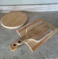 Three wooden cutting boards on concrete surface showing different shapes and sizes.