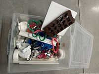 Overview of plastic tote container holding assorted baking and decorating supplies including cookie cutters, molds, and tools.