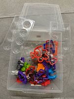 Clear plastic tote containing assorted colorful plastic cookie cutters and a clear plastic mold tray