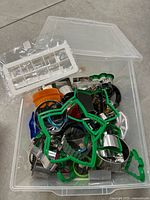 Clear plastic tote filled with assorted metal and plastic cookie cutters in various shapes and sizes, plus a clear plastic ice cube tray on top.