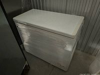 Front and side view of wrapped white chest freezer closed