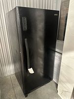 Front three-quarter view of black Kenmore upright freezer in storage unit showing handle and exterior
