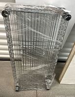 Photo showing multiple stainless steel wire shelves stacked and shrink-wrapped vertically.