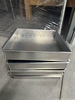 Stack of four stainless steel square pans showing size, edge design, and material finish