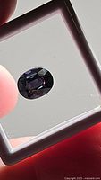 Front view of the oval cut purple spinel gemstone displayed under natural light in a display box.