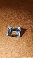 Natural aquamarine emerald cut gemstone showing light blue color and clear facets from one angle.