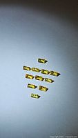Top down photo showing twelve baguette cut natural canary yellow sapphires laid out on a flat surface with light background.
