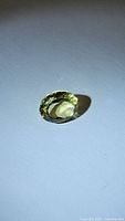 Oval cut lemon citrine gemstone on a white background, showing light yellow-green hues and clarity.