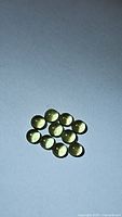 Eleven natural bright apple green round cabochon peridot gemstones arranged on white surface