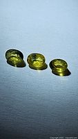 Three oval cut yellow sapphires displayed on a flat surface under natural light, showing clarity and color.
