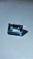 Close-up image of the rectangular baguette cut natural Swiss blue topaz gemstone showing its deep blue color and clarity.