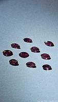 Ten marquis cut natural rubies displayed on a plain surface showing their size, shape, and color.