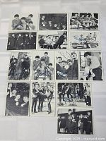 Display of sixteen 1964 Topps Beatles black and white trading cards arranged on a white background, showing group and individual band member images.