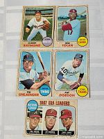 Five 1968 O-Pee-Chee baseball cards laid out on a surface, showing players Claude Raymond, Bob Tolan, Ted Uhlaender, Pat Dobson, and a group card of 1967 ERA leaders.
