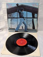 Vinyl record LP with red center label, placed on sleeve, showing disc condition.