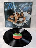 Photo of Boney M Nightflight to Venus vinyl record partially pulled out of its original album cover, showing the green and red Atlantic record label on the disc.