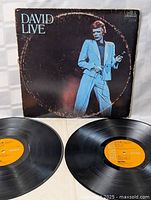 Front view of David Bowie LIVE album cover and two vinyl records with orange RCA Victor labels in front of it.